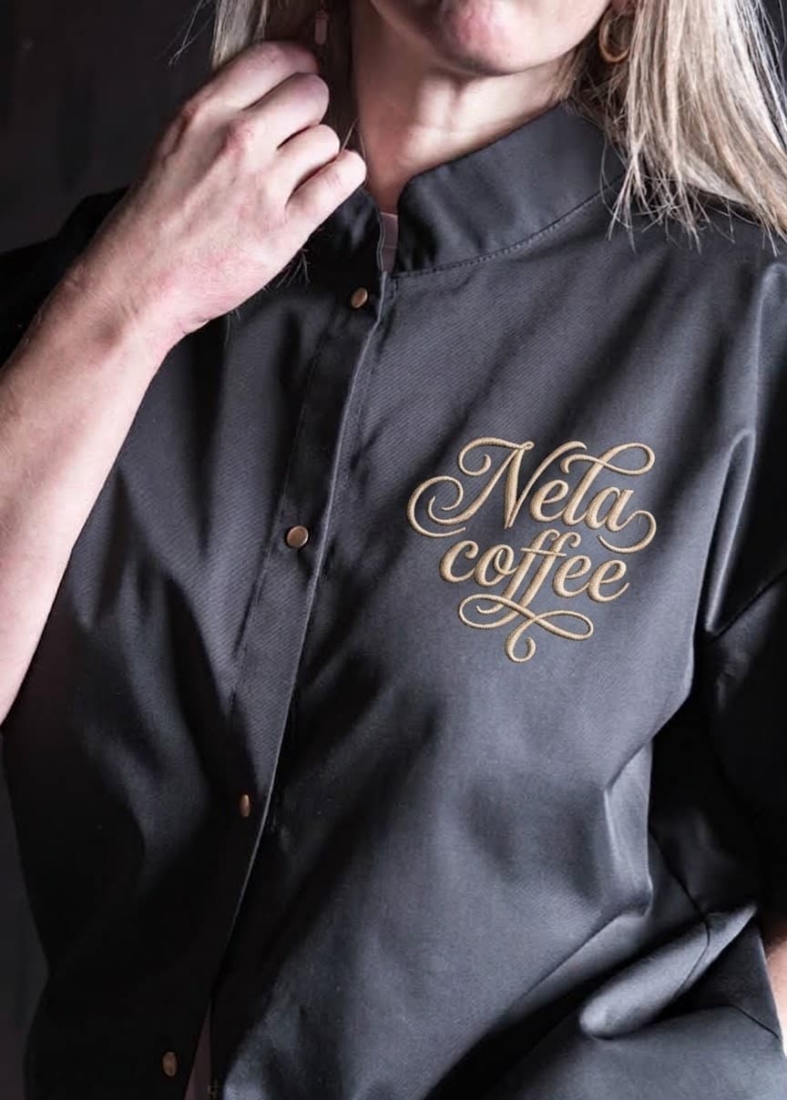 Zlatá výšivka loga Nela coffee na grafitovém rondonu
